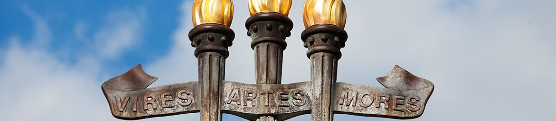 Photo of the top of the University Center's three torches fountain of Vires, Artes, Mores