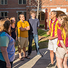 Photo of orientation leaders stopped in front of a residency hall while touring with students through campus
